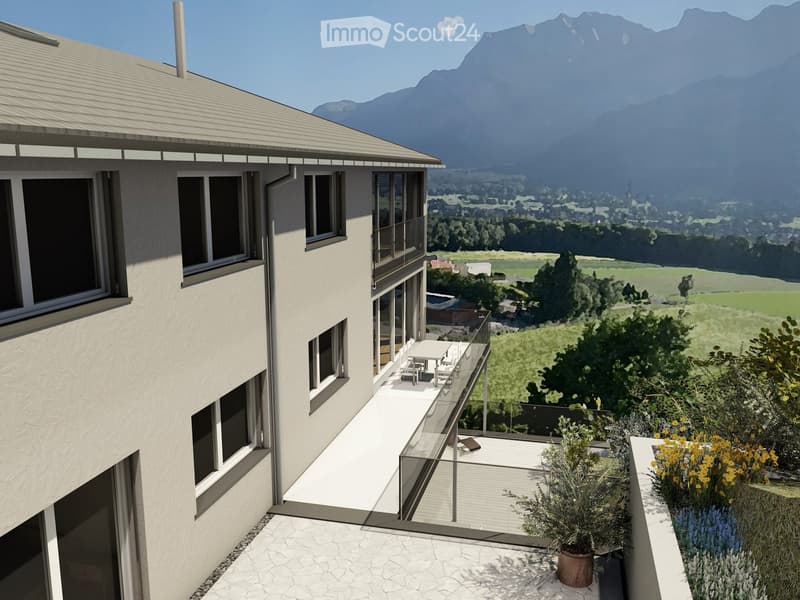 Modern multi-story building with large windows, balconies, and a scenic view of the surrounding mountains and countryside