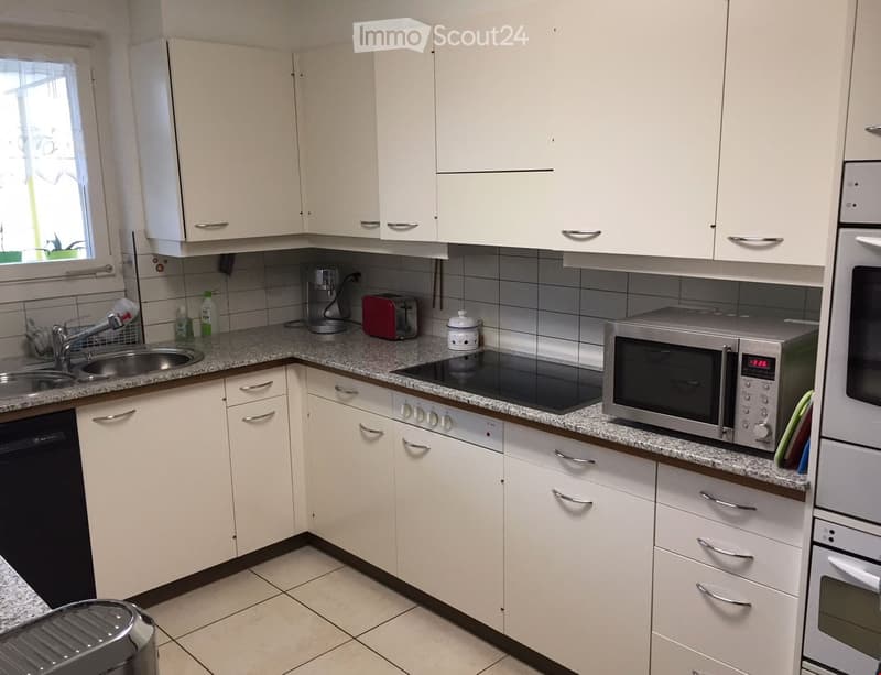 Modern kitchen with white cabinets, granite countertops, and stainless steel appliances including a microwave, oven, and dishwasher.
