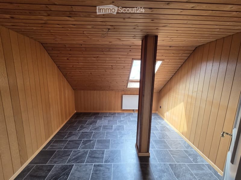 Wooden-paneled hallway with dark tiled floor, slanted wooden ceiling, and small skylight windows.
