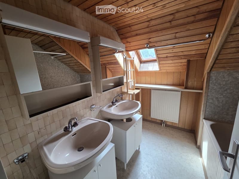 Modern bathroom with two sinks, wooden ceiling, tiled walls, and built-in cabinets.