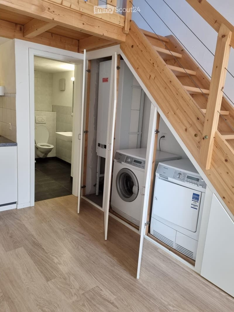 Laundry room with washing machine and dryer, wooden stairs, tiled bathroom