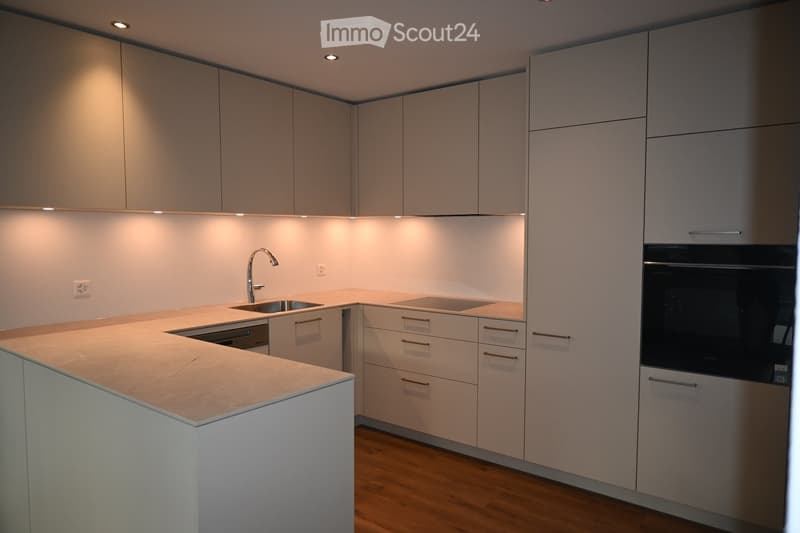 Sleek white cabinets, granite countertops, modern appliances including sink, dishwasher, and oven.