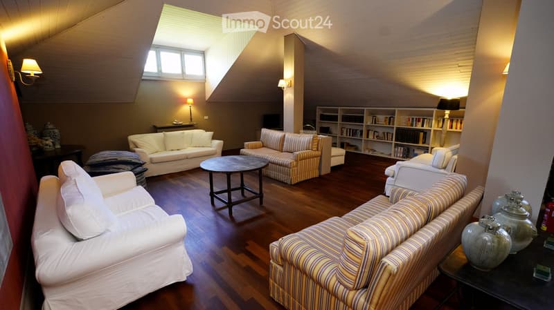 Living room with wooden flooring, multiple sofas, coffee table, bookshelf, and decorative vases.