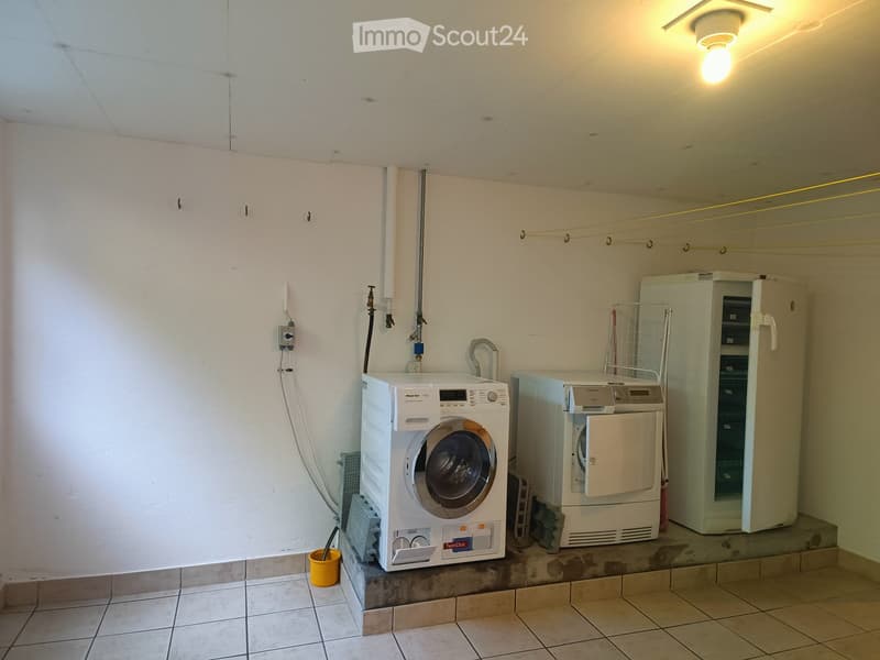 Utility room with a washing machine, dryer, and refrigerator. The room has tiled flooring and white walls.