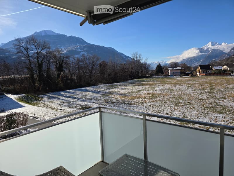 Balcony with a view of a snow-covered field and mountains in the background.