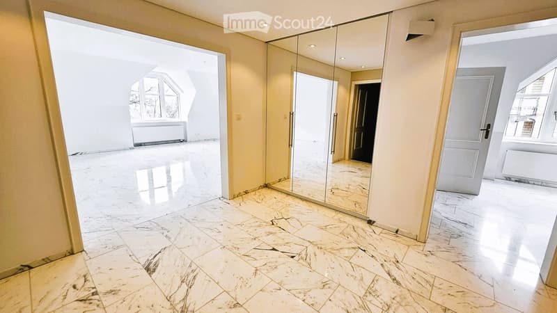 Empty hallway with polished marble flooring, large mirrored wall, and multiple open doorways leading to other rooms.