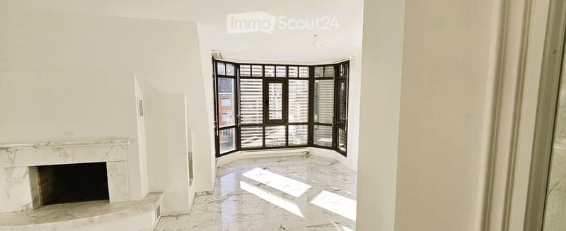 Empty room with a marble fireplace, large windows with blinds, and a polished marble floor.