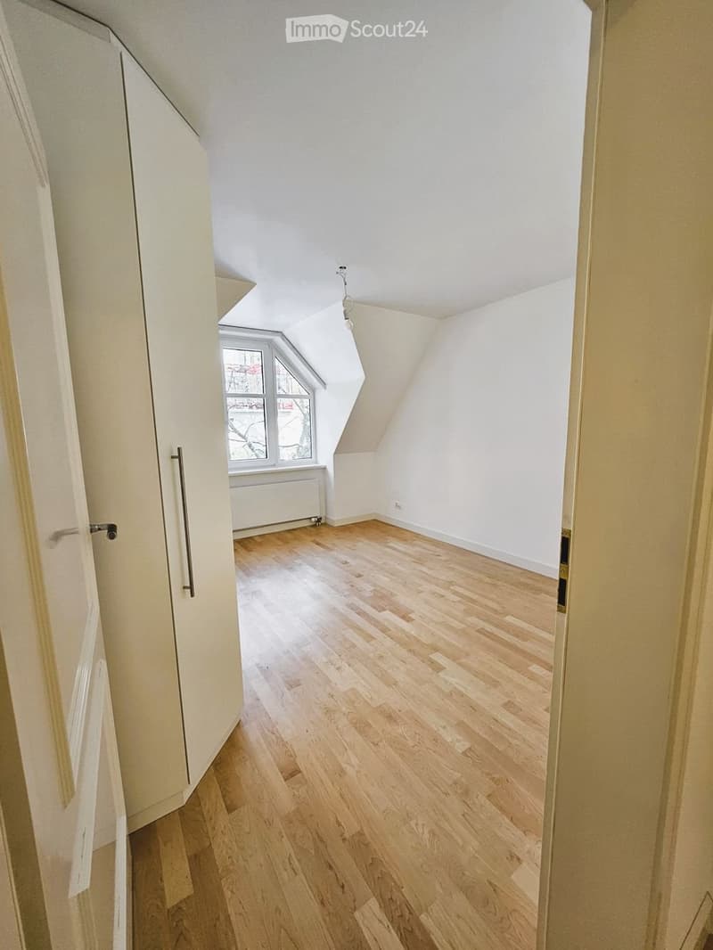 Empty attic room with wooden flooring, white walls, and a skylight window. No furniture or equipment present.
