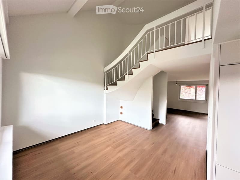 Empty hallway with wooden flooring, white walls, and a staircase leading to an upper level. The space is clean and unfurnished, with no visible furniture or decorations.