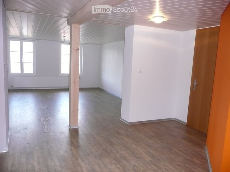 empty room with wooden floor, white walls, ceiling light, 2 windows, a pillar, and a door
