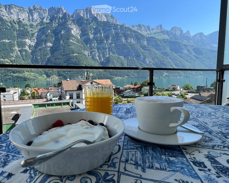 Breakfast setup on a balcony with a stunning mountain and lake view in the background.