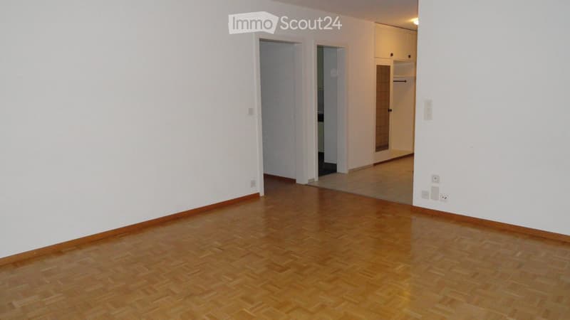 Empty room with wooden flooring and white walls, featuring two open doorways leading to adjacent spaces.