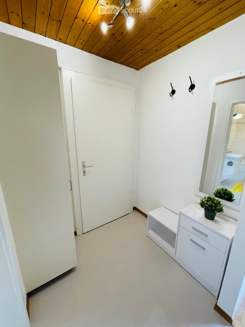 empty room with white walls and ceiling, white door, white shelves, mirror with two plant pots, and two wall hooks