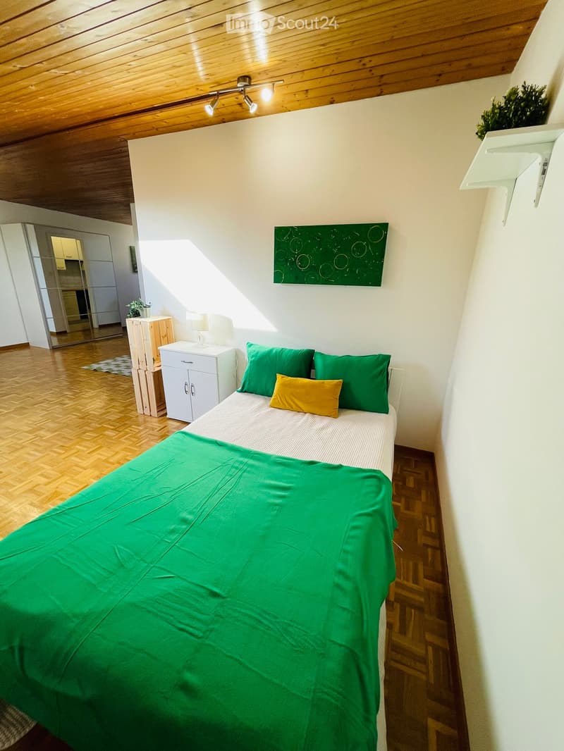 small bedroom with bed, nightstand, plants, painting, wooden floor, white walls