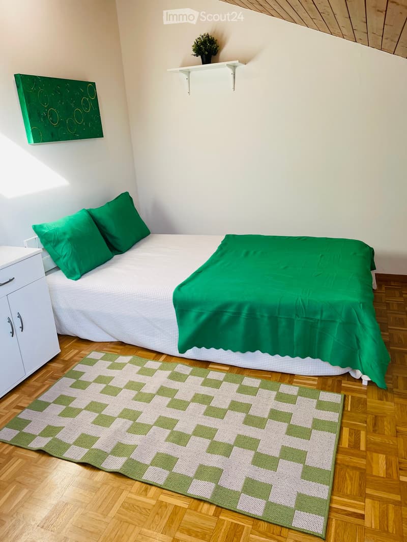 single bed, green blanket, white and green rug, green pillows, white cabinet