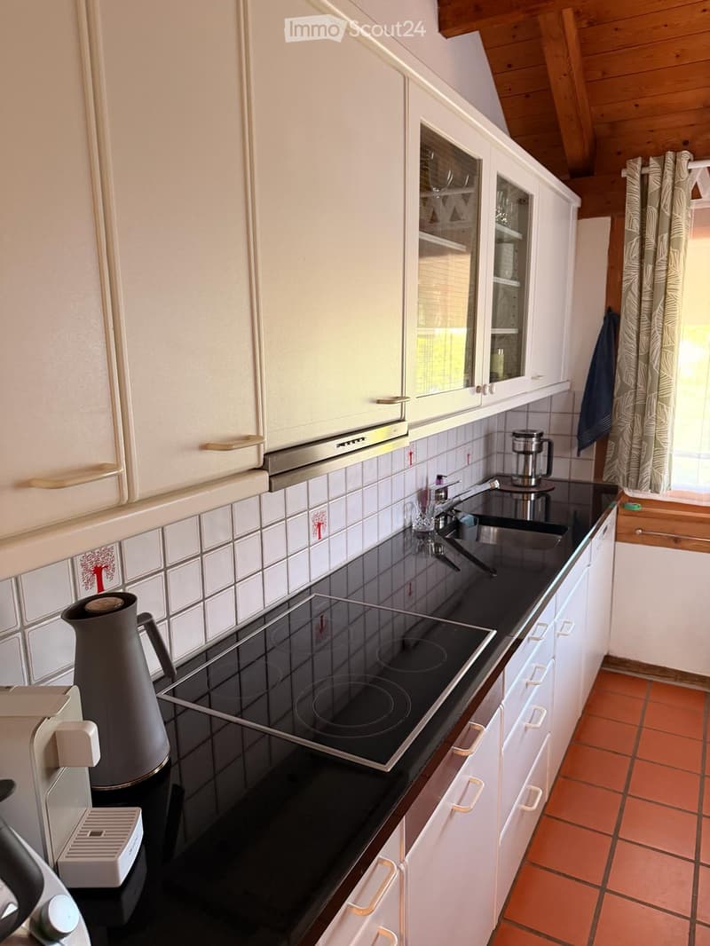 Modern kitchen with white cabinets, black countertops, electric stove, sink, and various appliances.
