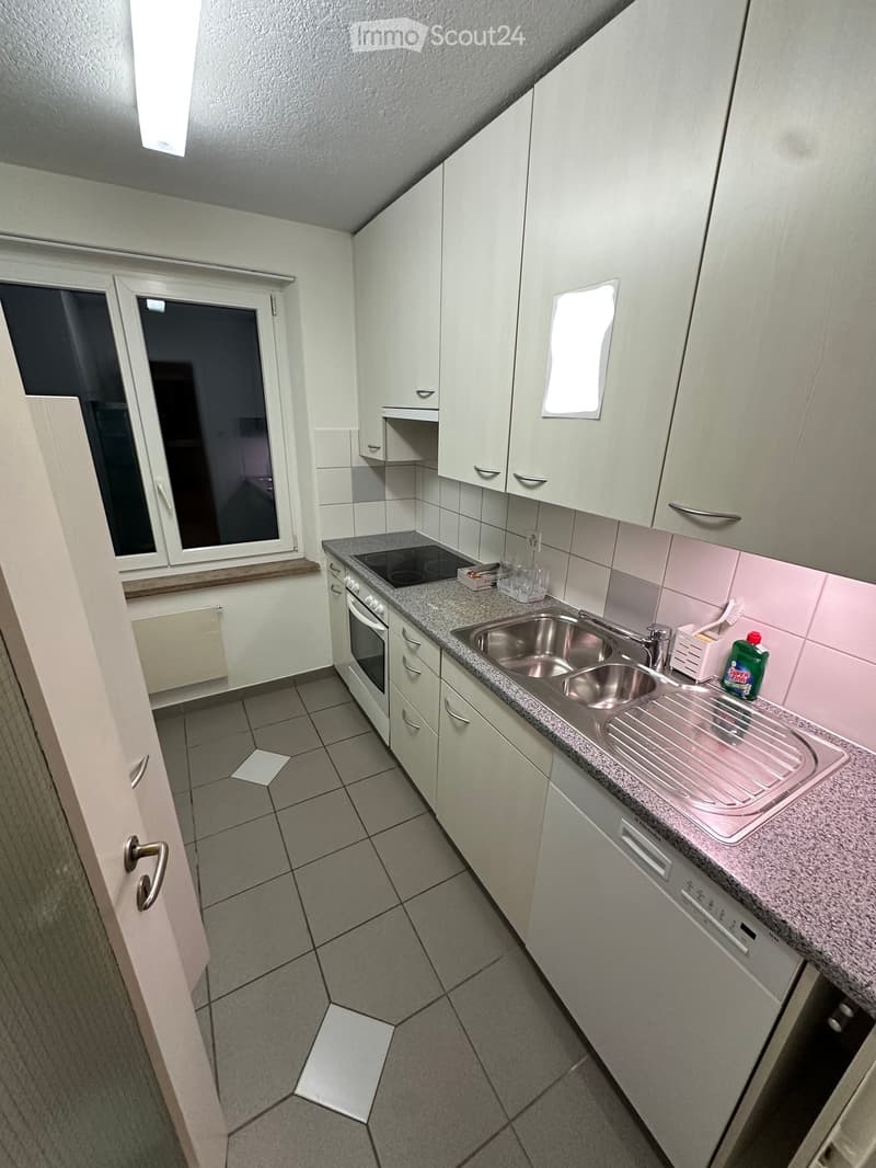 Modern kitchen with white cabinets, granite countertop, stainless steel sink, oven, and various small appliances.