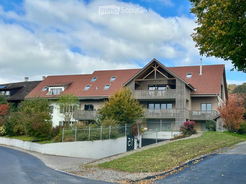 Two-story house with red-tiled roof, multiple windows, balconies, and a fenced front yard.