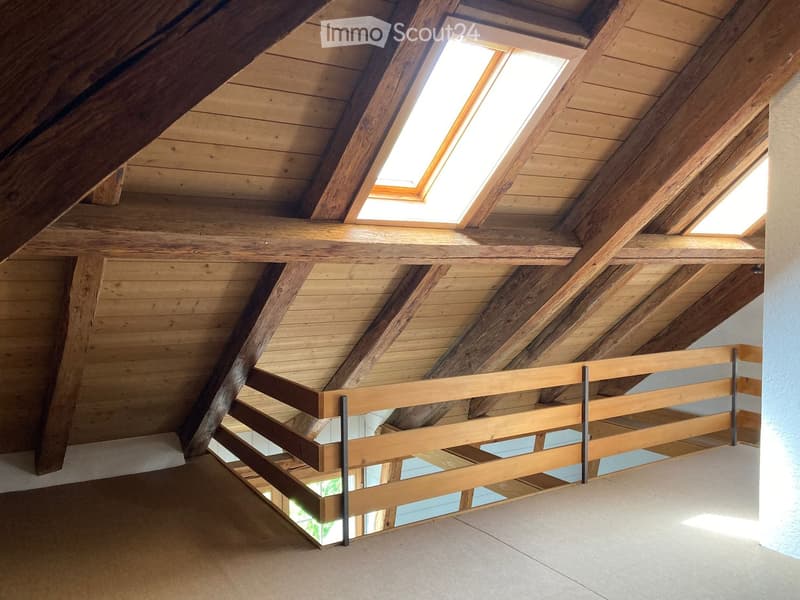 Unfurnished Room. An attic space with exposed wooden beams and skylights, featuring a wooden railing and a concrete floor.