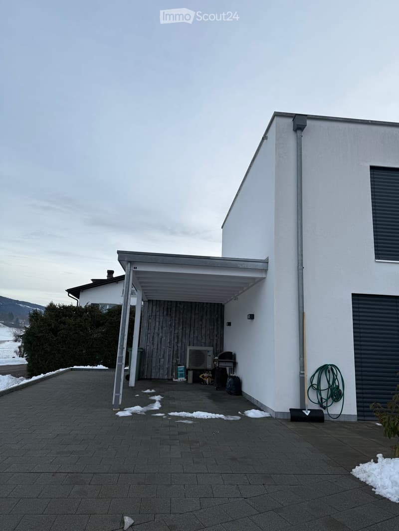 Outdoor patio area with a covered section, air conditioner, grill, and garden hose coiled against the wall.