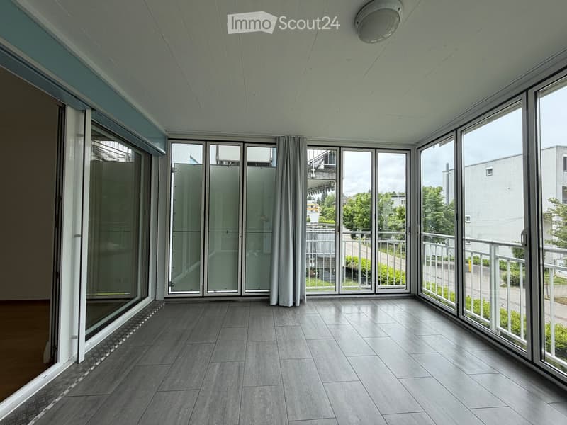 Empty balcony with large glass doors, tiled floor, and white walls.