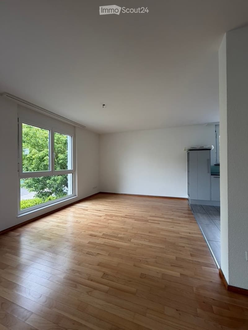 Completely empty room with wooden flooring, large windows, and white walls. No furniture or equipment present.