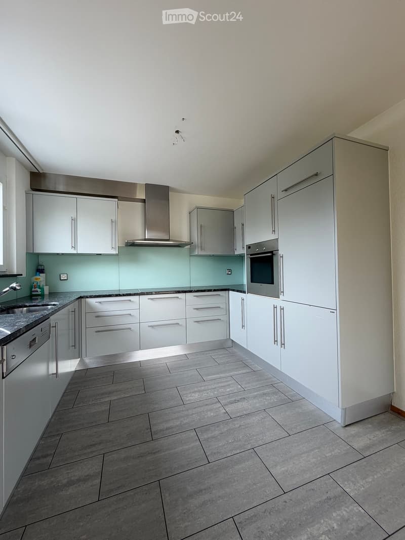 Modern kitchen with white cabinets, stainless steel appliances, granite countertops, and tiled flooring.