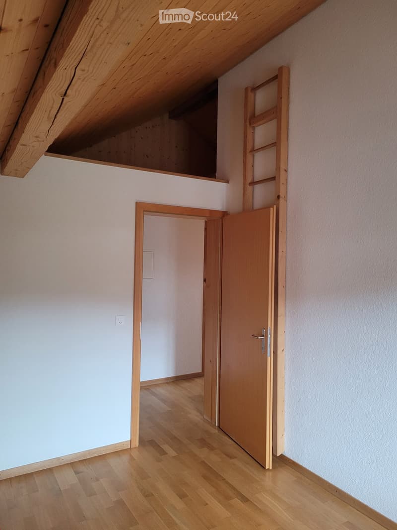 Empty hallway with wooden flooring, white walls, and two open wooden doors leading to other rooms.