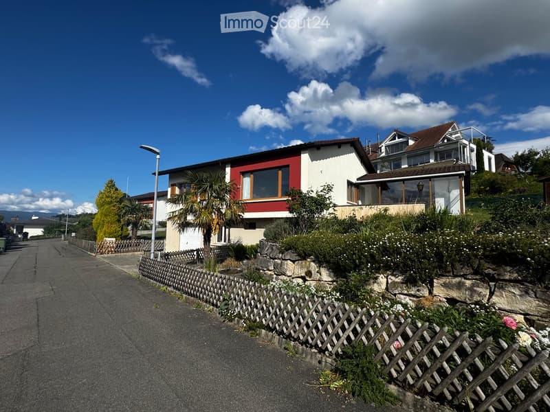 House. Two-story house with red and white exterior, large windows, and a well-maintained garden with a wooden fence.