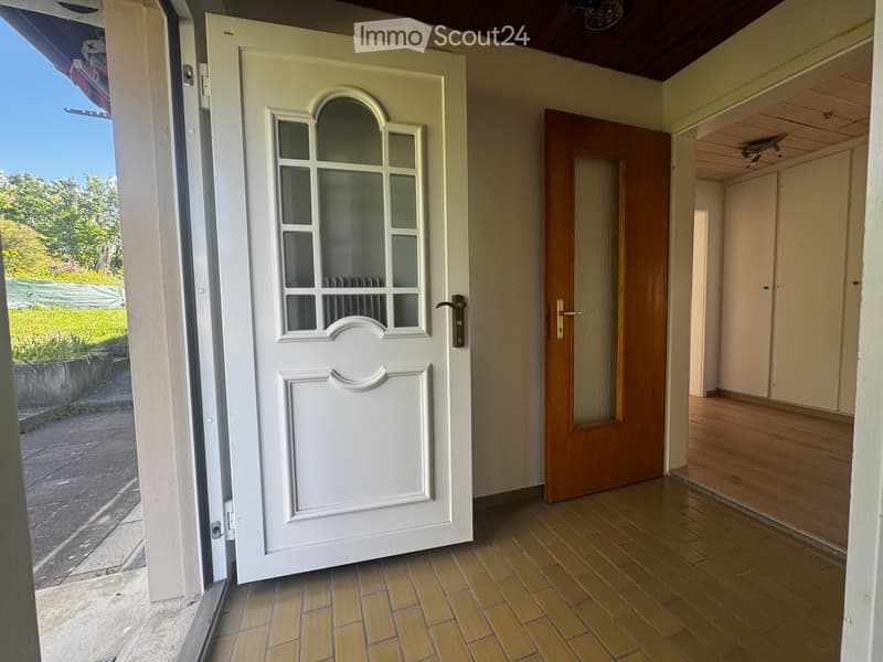 Corridor / Hallway. Entrance hallway with a white front door featuring glass panels, a wooden interior door, and wooden flooring.