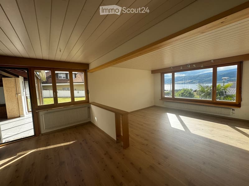 Unfurnished Room. Bright, empty room with wooden flooring, large windows offering scenic views, and built-in wooden beams on the ceiling.