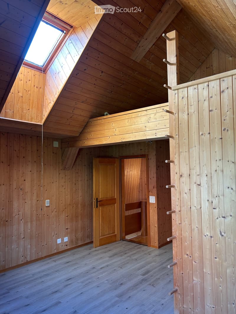 Empty wooden room with exposed beams, skylight, and built-in loft area. Features wooden walls, floor, and doors.
