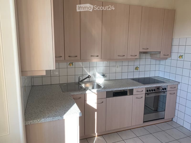 Modern kitchen with light wood cabinets, granite countertop, stainless steel sink, faucet, oven, and dishwasher.