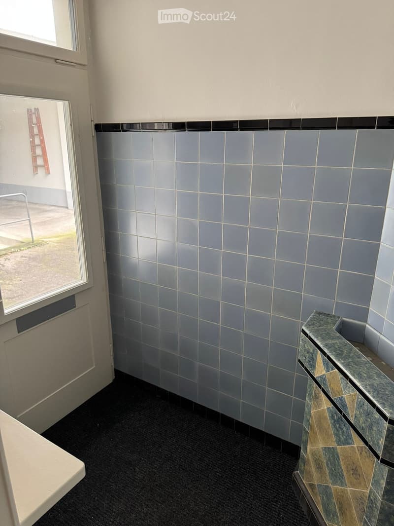white door, light blue tiles, black carpet, metal railing, window with metal fencing