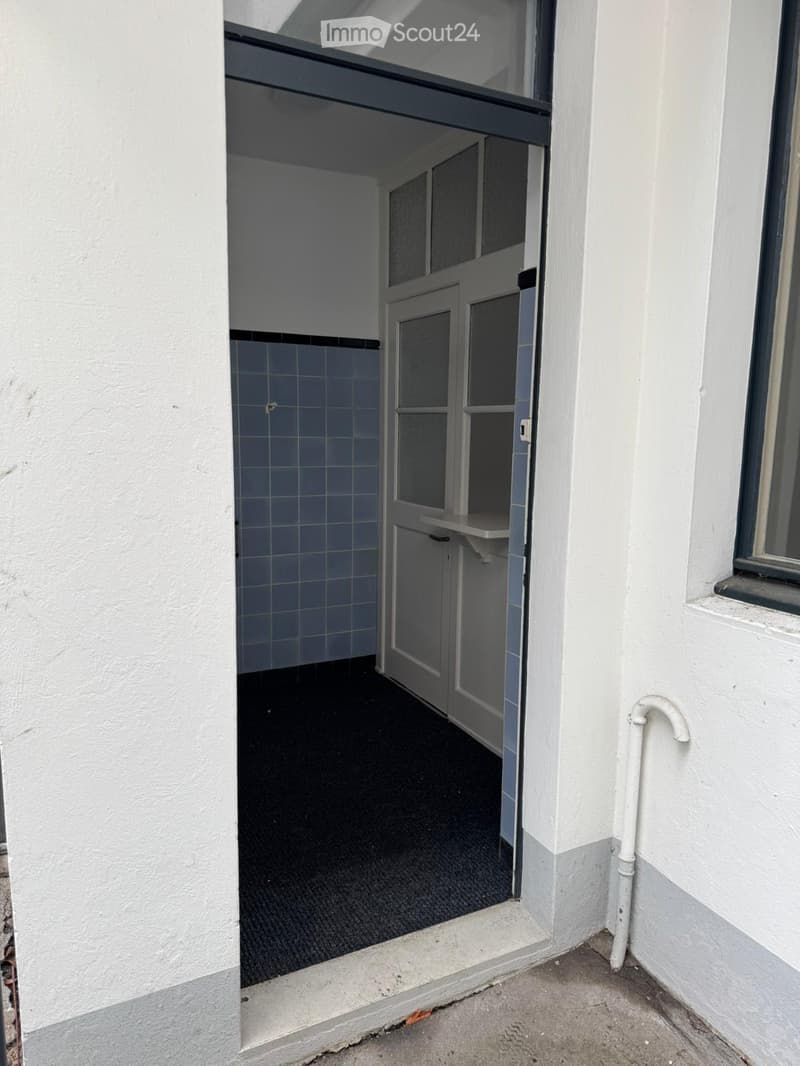 Entrance room with tiled walls, black carpet, white door, shelf, open door