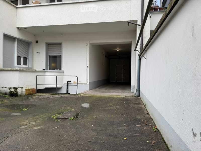 parking area, paved, white building with windows, garage, small drain