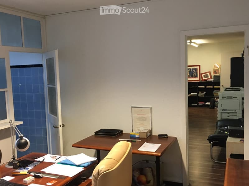 Office room with wooden desk, beige office chair, lamp, papers, office supplies, framed certificate
