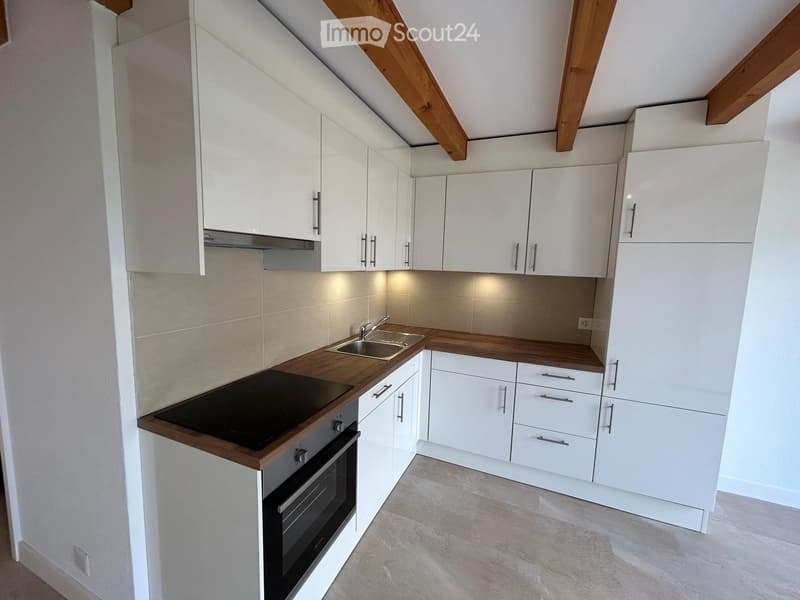 Modern kitchen with white cabinets, wooden countertops, and stainless steel appliances including a stove, oven, and sink.
