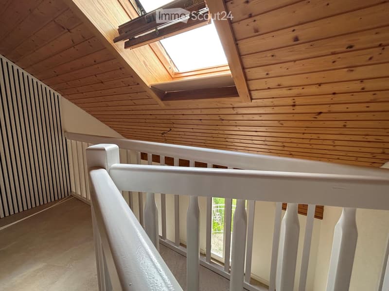 Wooden ceiling with skylight, white railing, and striped wall paneling.