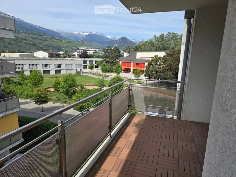 Balcony with wooden decking, metal railing, and scenic mountain view.