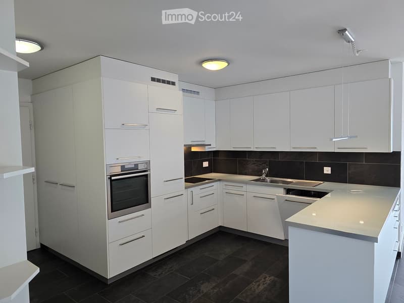 Modern kitchen with white cabinets, stainless steel appliances, dark tiled floor, and a central island.