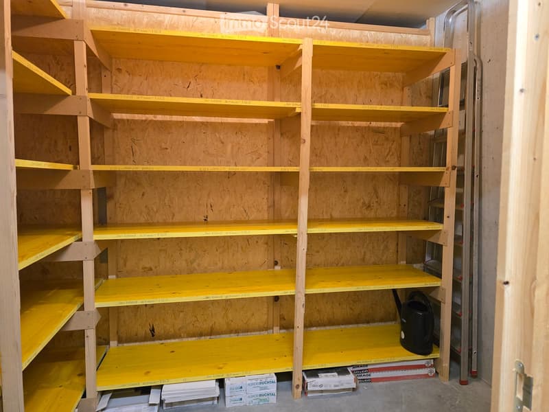Empty storage room with wooden shelves and yellow measuring tape markings on the walls. No furniture or equipment present.