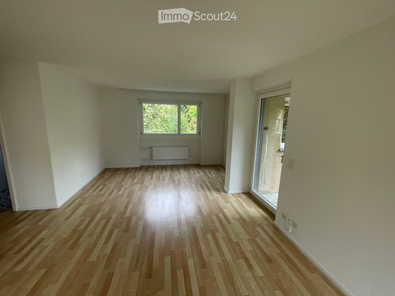 Empty room with light wooden flooring, white walls, and large windows allowing natural light. No furniture or equipment is present.
