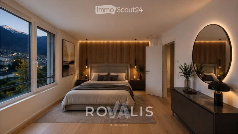 Modern bedroom with large windows offering a scenic mountain view, featuring a bed with pillows and a duvet, nightstands, a round mirror, a table with a lamp, and decorative plants.