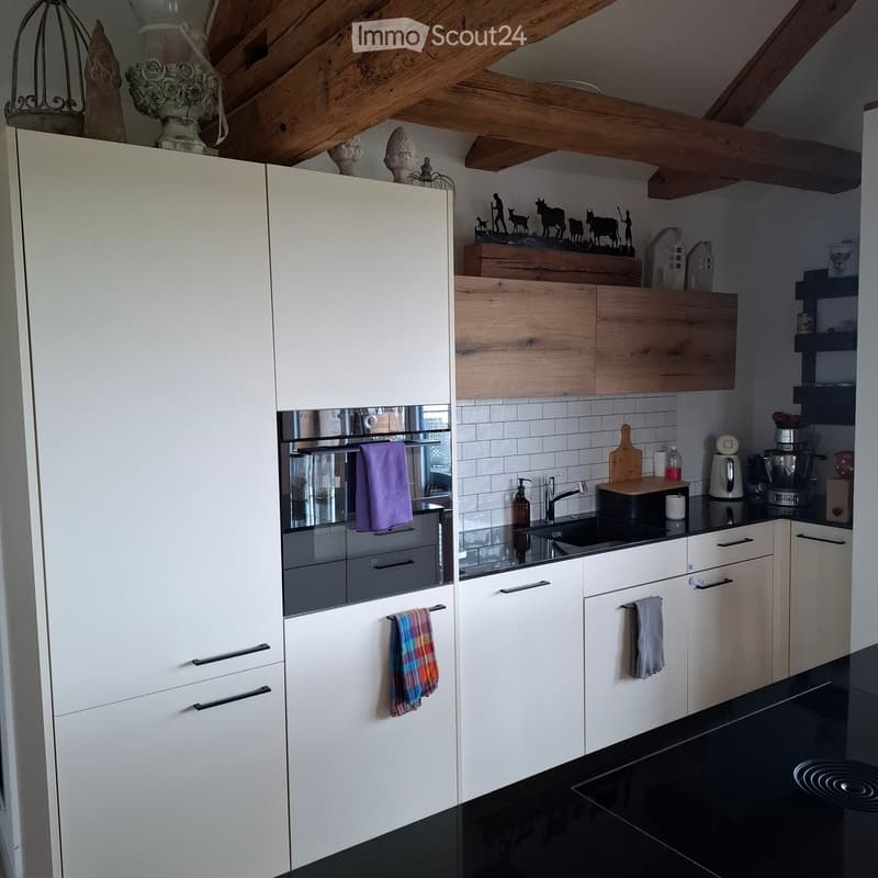 Kitchen. Modern kitchen with white cabinets, black countertops, and wooden beams. Equipped with a sink, oven, and various kitchen appliances.