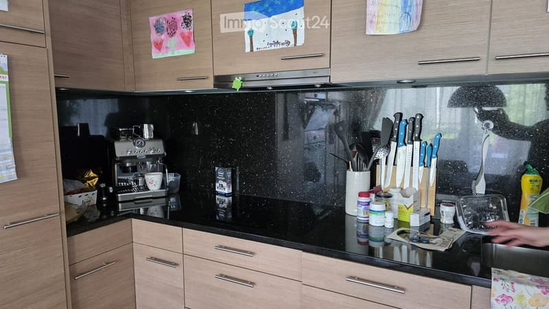 Modern kitchen with wooden cabinets, black countertop, coffee maker, and various kitchen utensils.