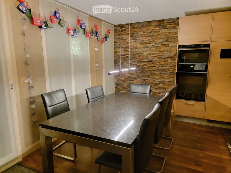Modern dining area with a sleek black dining table, four black leather chairs, and a built-in oven with light wood cabinetry.