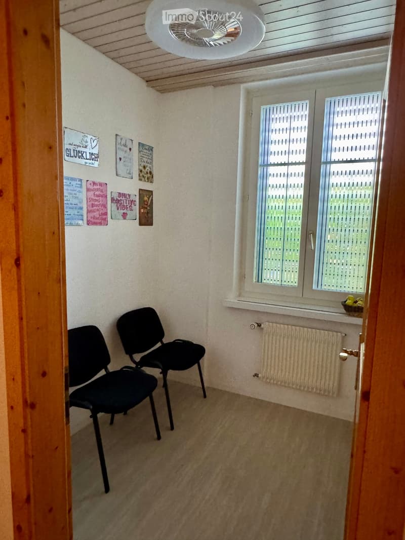 Small room with two black chairs, a radiator, a window with blinds, and a ceiling fan.