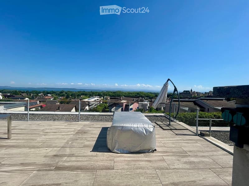Roof terrace with wooden decking, covered furniture, umbrella, and scenic city view.