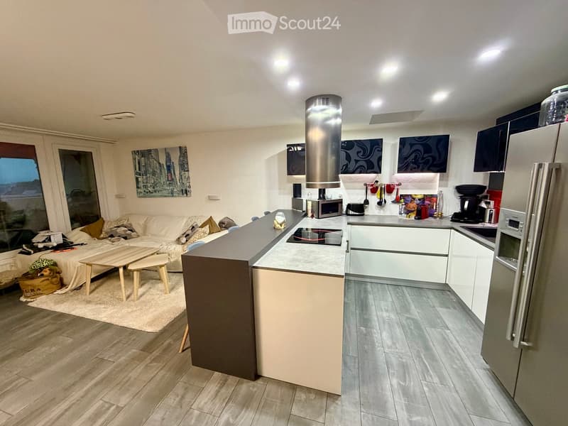 Modern open-plan living and kitchen area with a sofa, coffee table, kitchen island, and various appliances.